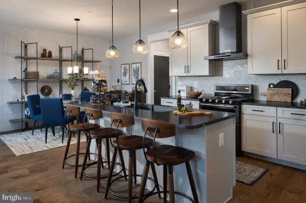 a kitchen with stainless steel appliances granite countertop a stove a sink a refrigerator and chairs
