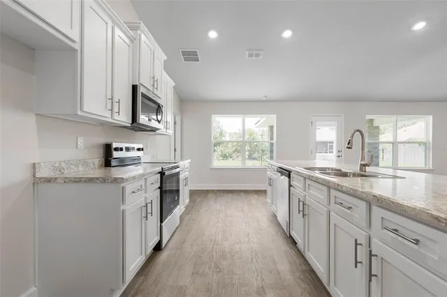 a large kitchen with stainless steel appliances granite countertop a lot of counter space and a sink