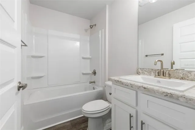 a bathroom with a granite countertop toilet a sink and a bathtub