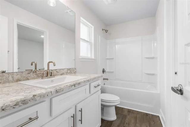 a bathroom with a granite countertop sink a toilet and bathtub