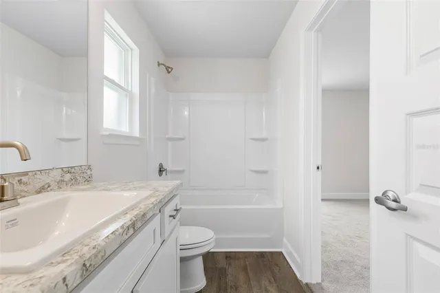 a bathroom with a granite countertop sink a toilet and shower