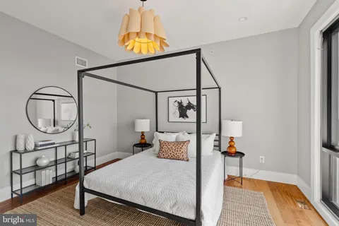 a bedroom with a bed a table and painting on the wall