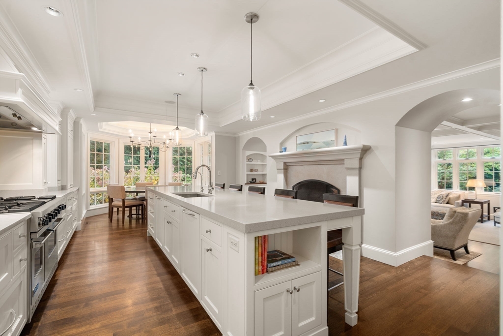 14 Greylock Road Wellesley, MA 02481 - Photo 9 of 24 a large white kitchen with stove a sink a dining table and chairs with wooden floor