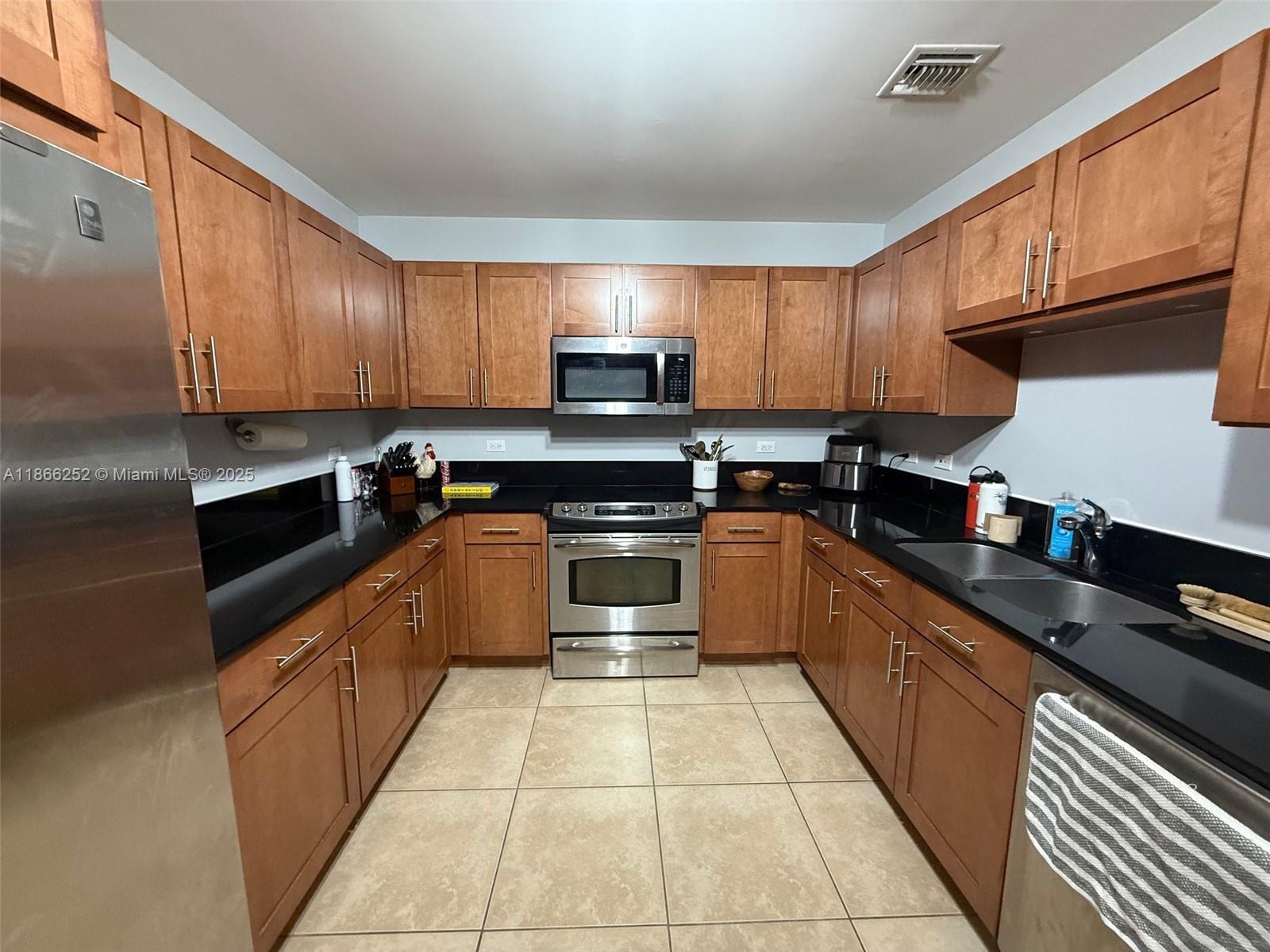 8395 Southwest 73rd Avenue, Unit 509 Miami, FL 33143 - Photo 10 of 41 a kitchen with granite countertop a stove top oven microwave and cabinets