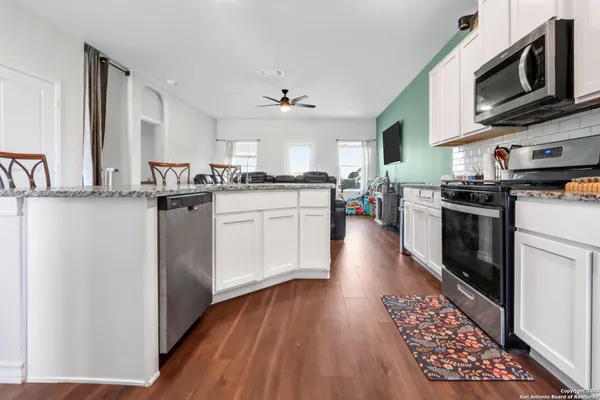 a kitchen with stainless steel appliances granite countertop a sink a stove a refrigerator cabinets and a dining table