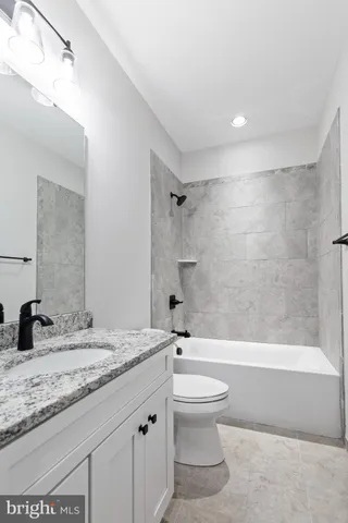 a bathroom with a granite countertop sink a toilet and shower