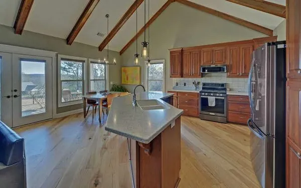 a kitchen with stainless steel appliances granite countertop a stove top oven a sink dishwasher a dining table and chairs with wooden floor