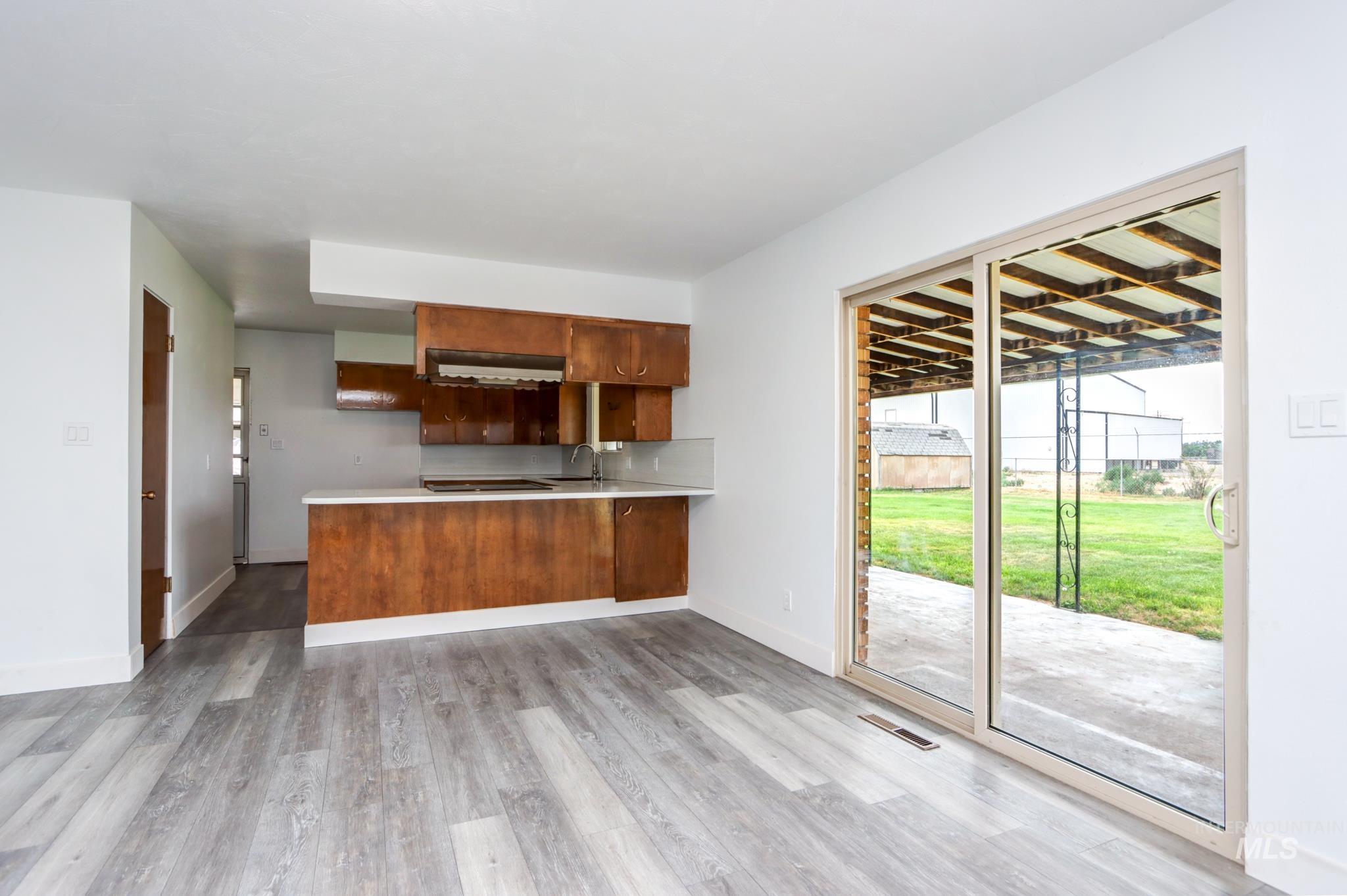 801 Thompson Avenue Nyssa, OR 97913 - Photo 5 of 46 Open-concept living area featuring light wood-finish flooring, a kitchen with wood cabinetry and light countertops, and a sliding glass door providing access to an outdoor patio area