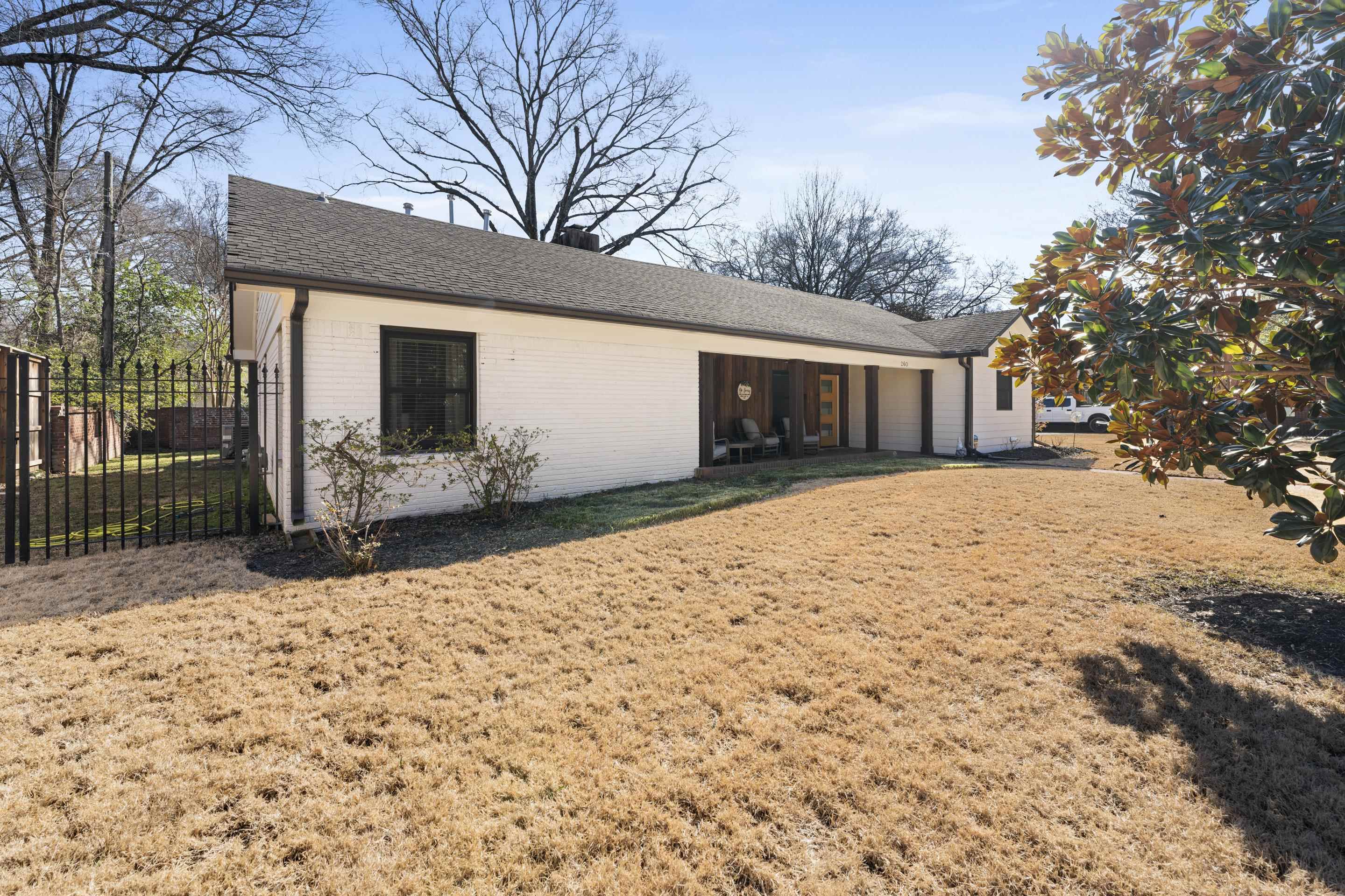 260 South Fenwick Road Memphis, TN 38111 - Photo 33 of 40 Well-maintained lawn and mature trees providing shade. The crisp white exterior with black trim gives it a modern touch, complemented by a covered patio.