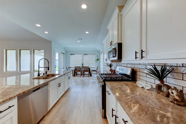 a large kitchen with granite countertop a large counter top appliances and cabinets