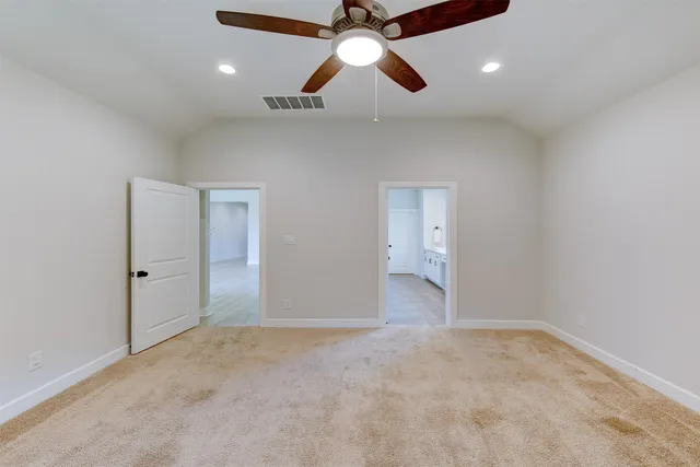an empty room with chandelier fan and windows