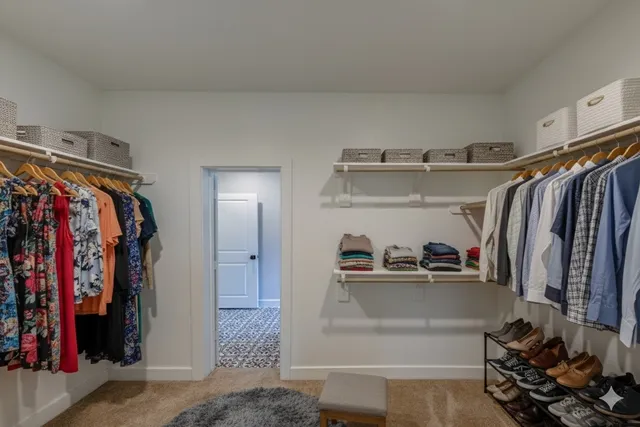 a view of walk in closet with clothes and shoes