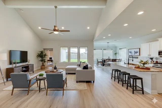 a living room with furniture a flat screen tv and kitchen view