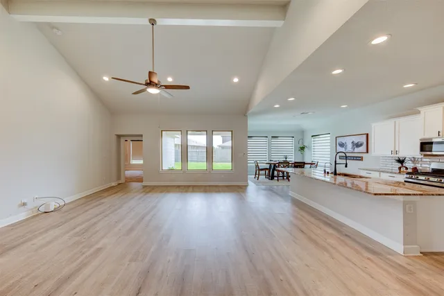a view of a living room a livingroom with furniture wooden floor kitchen and windows
