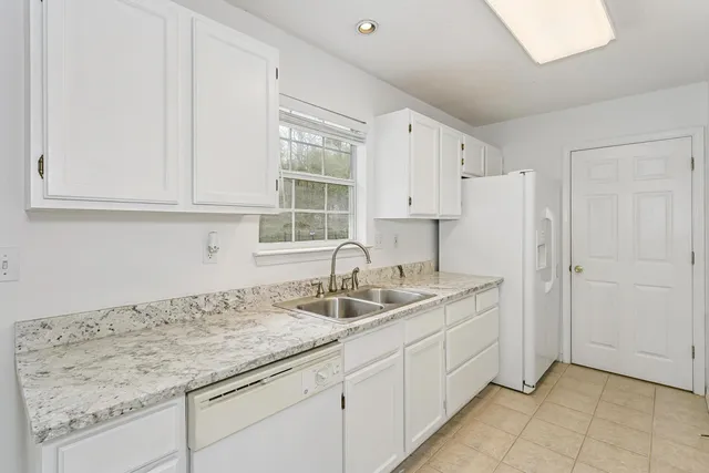 a kitchen with granite countertop a sink and white cabinets
