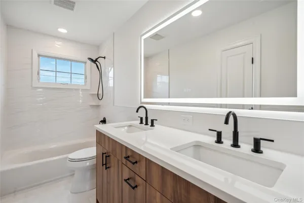a bathroom with a double vanity sink toilet and a bathtub