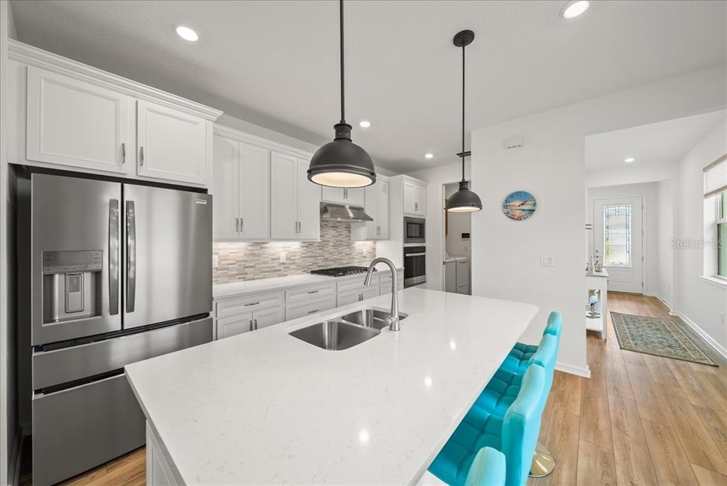 9434 Ballaster Pointe Loop Palmetto, FL 34221 - Photo 16 of 66 a kitchen with stainless steel appliances kitchen island granite countertop a refrigerator a sink a stove and white cabinets with wooden floor
