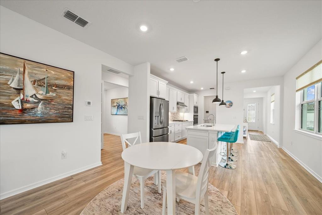 9434 Ballaster Pointe Loop Palmetto, FL 34221 - Photo 17 of 66 a kitchen with stainless steel appliances kitchen island granite countertop a refrigerator a stove a microwave oven a dining table and chairs with wooden floor