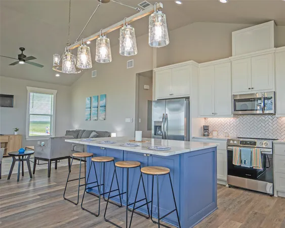 a kitchen with cabinets a sink dining table and stainless steel appliances