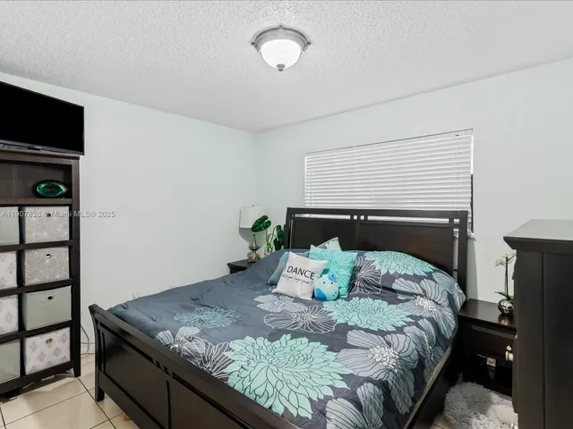 a bedroom with a bed and a flat tv screen on dresser