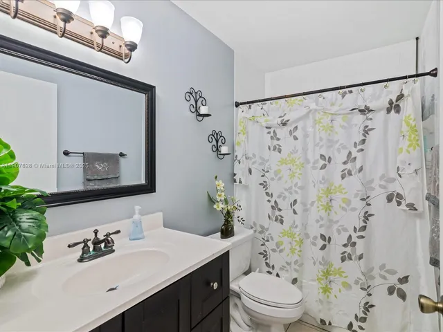 a bathroom with a sink toilet a mirror and shower curtain