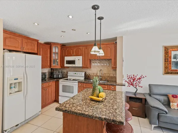 a kitchen with stainless steel appliances granite countertop a sink refrigerator and cabinets