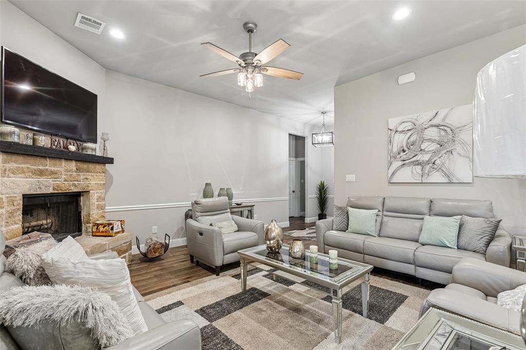 108 Maverick Lane Pilot Point, TX 76258 - Photo 6 of 27 Spacious living area featuring a stone-clad fireplace with a dark wood mantel, wood-finish flooring, recessed lighting, crown molding, and a ceiling fan with integrated lighting