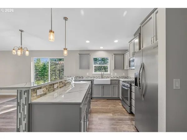 a kitchen with stainless steel appliances granite countertop a refrigerator a sink dishwasher a stove and white cabinets with wooden floor