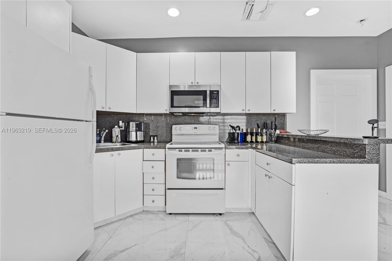 14651 Southwest 16th Street Davie, FL 33325 - Photo 35 of 52 a kitchen with granite countertop white cabinets and white appliances