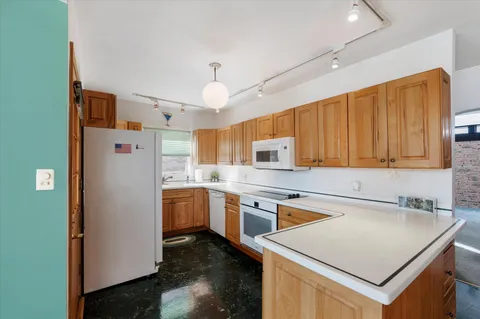 a kitchen with a refrigerator a sink dishwasher and wooden cabinets with wooden floor