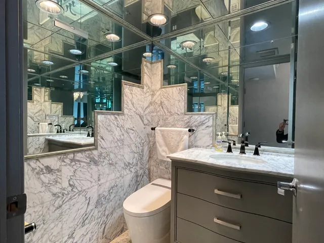 a view of a hallway with wooden floor and a bathroom