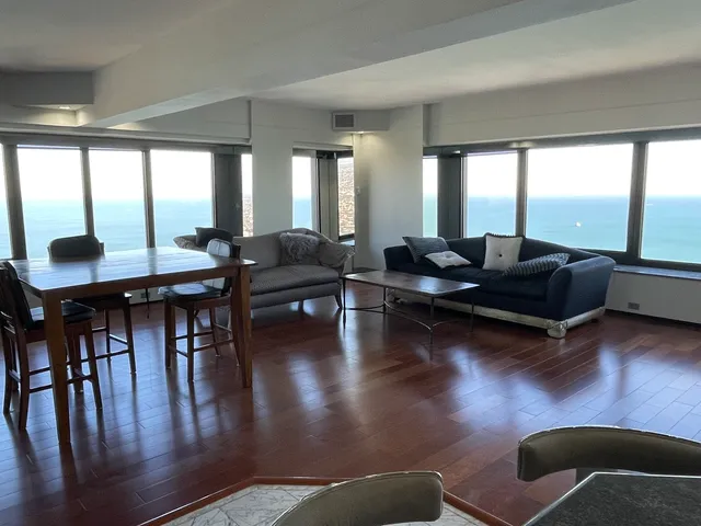 a living room with couches bookshelf and a large window