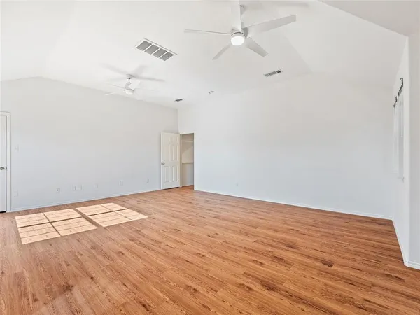 an empty room with wooden floor ceiling fan and window