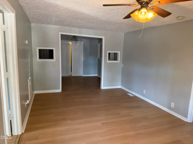 a view of an empty room with window and wooden floor