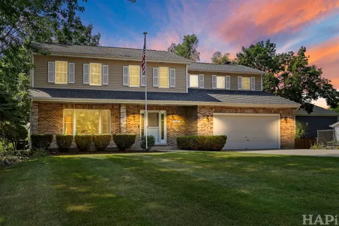 a front view of a house with a yard and potted plants