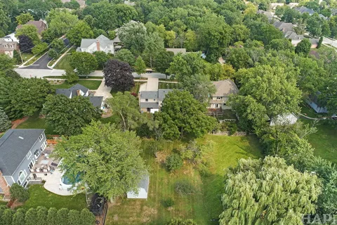 an aerial view of residential house with outdoor space and trees all around