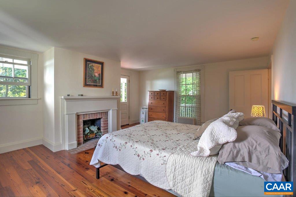 528 Top Ridge Road Stanardsville, VA 22973 - Photo 21 of 45 a bed sitting in a bedroom next to a window with fireplace
