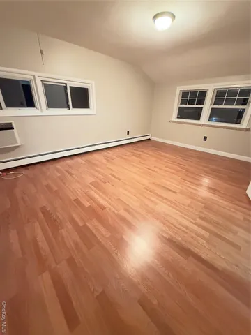 a view of an empty room with window and wooden floor