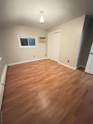 a view of an empty room with wooden floor and windows