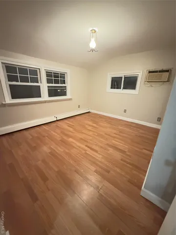 a view of empty room with wooden floor and window