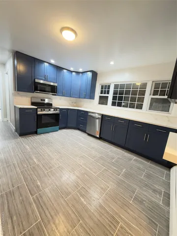 a large kitchen with stainless steel appliances a large counter top a stove and a refrigerator