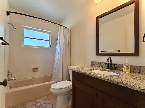 a bathroom with a granite countertop sink mirror vanity and toilet