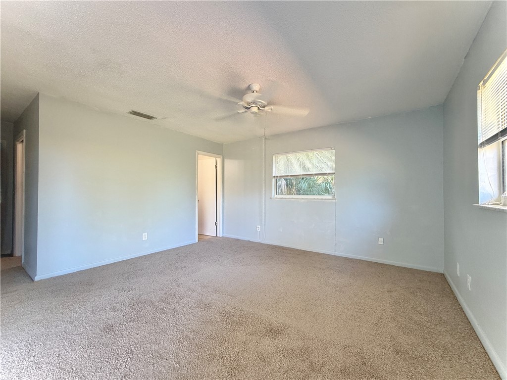 715 Holly Road Vero Beach, FL 32963 - Photo 16 of 25 an empty room with windows and chandelier fan
