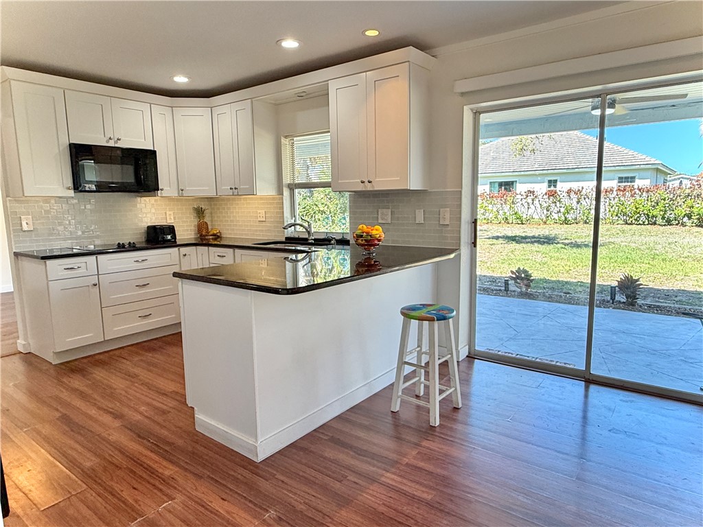 715 Holly Road Vero Beach, FL 32963 - Photo 9 of 25 a kitchen with kitchen island granite countertop wooden floors and white stainless steel appliances
