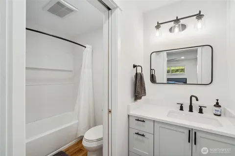 a bathroom with a granite countertop sink vanity mirror and toilet