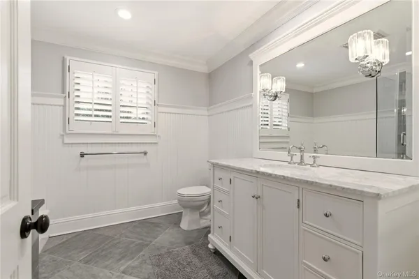 a bathroom with a granite countertop toilet a sink a mirror and a window