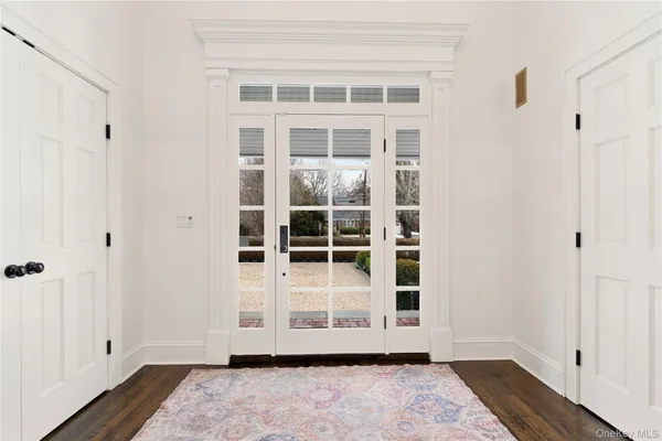 a view of front door with wooden floor and white walls