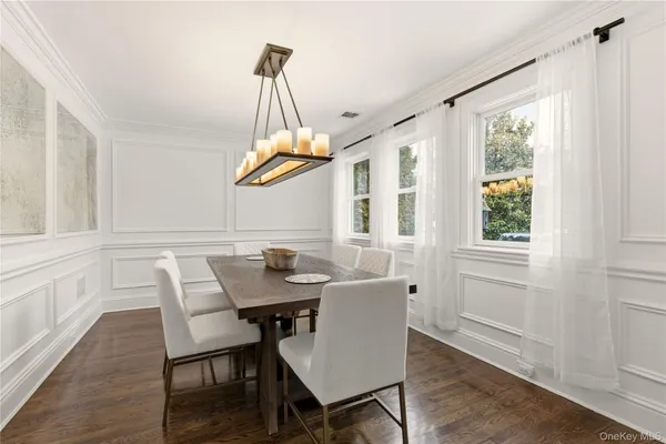 a dining room with wooden floor a chandelier a wooden table and chairs