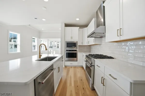 a large kitchen with stainless steel appliances granite countertop a lot of counter space and wooden floors