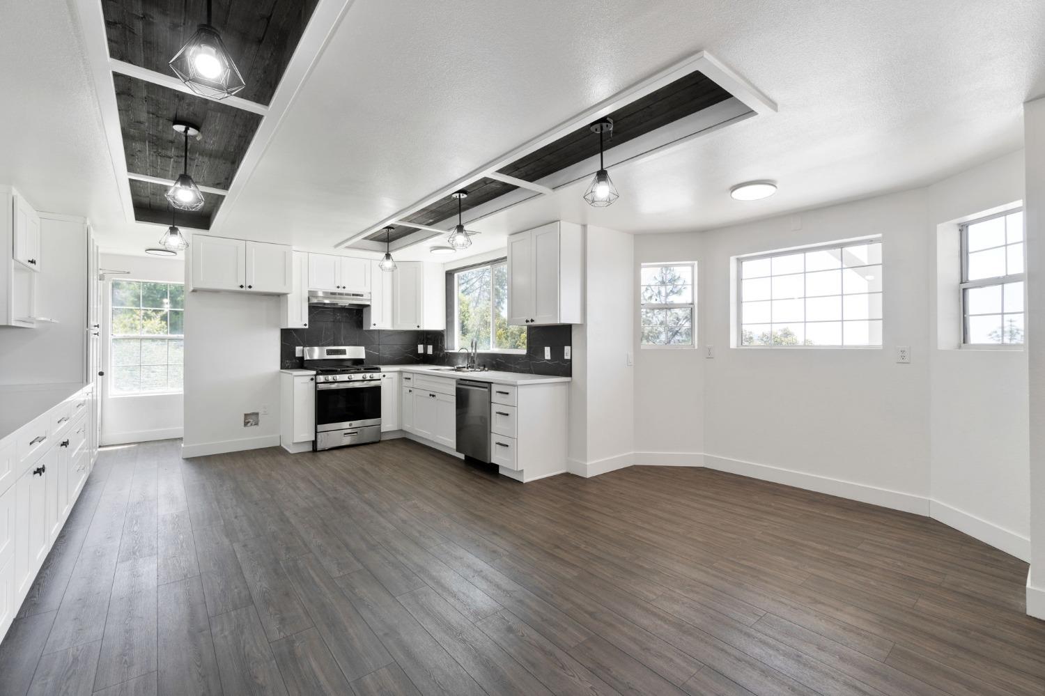 2832 East Westfall Road Mariposa, CA 95338 - Photo 7 of 38 a kitchen with stainless steel appliances kitchen island wooden floors and white cabinets